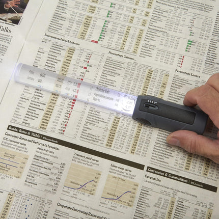 2x magnification bar magnifier highlighting small text in newspaper with LED lights