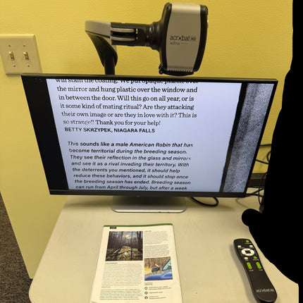 Monitor displaying text on a desk with a magazine and remote control