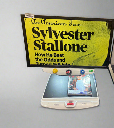 Book titled 'An American Icon: Sylvester Stallone' with a scanner and digital camera on a gray surface.