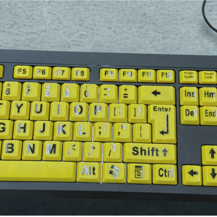 Large print computer keyboard with bright yellow keys and bold black letters for enhanced visibility.