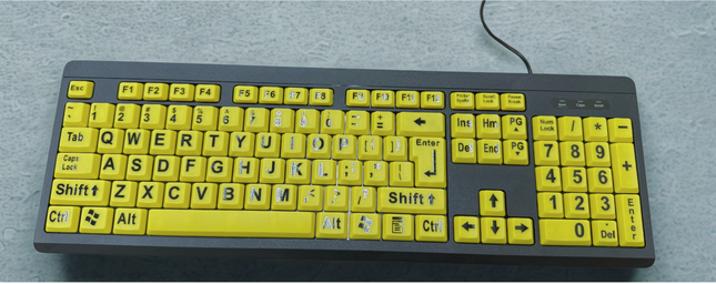 Large print computer keyboard with bright yellow keys and bold black letters for enhanced visibility.