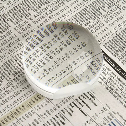 2.5 inch dome magnifier on newspaper, enhancing visibility of detailed text and information.