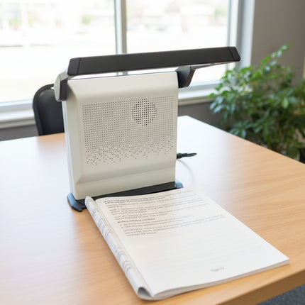 Book being read by a document camera on a desk with a remote control nearby.