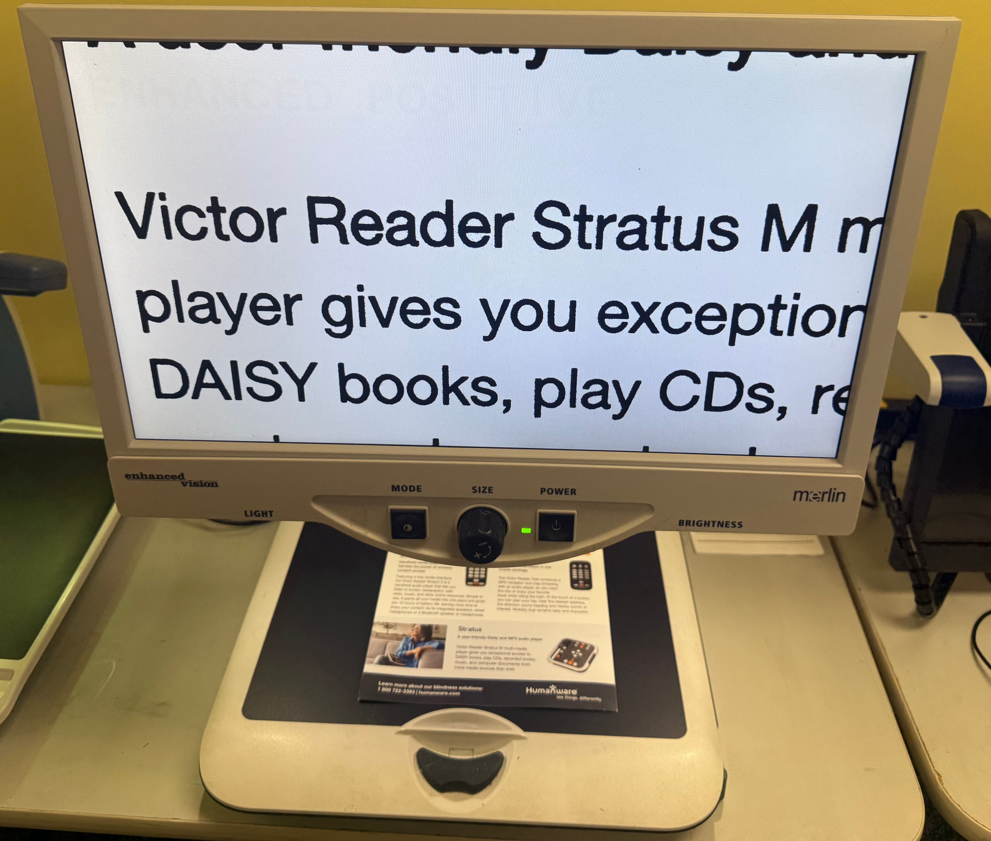 Victor Reader Stratus M machine on a table with a yellow wall background