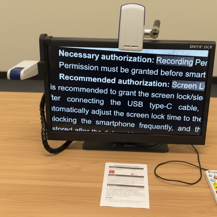ONYX 24 inch HD magnifier with text to speech displaying enlarged document on 24-inch screen with remote and controls on desk