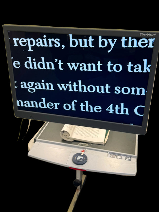 Monitor displaying text on a desk with a book underneath