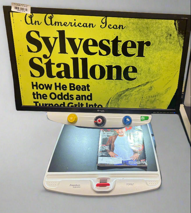 Book titled 'An American Icon: Sylvester Stallone' with a scanner and digital camera on a gray surface.