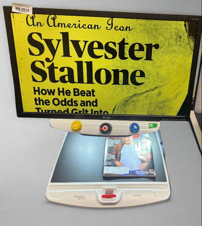 Book titled 'An American Icon: Sylvester Stallone' with a scanner and digital camera on a gray surface.