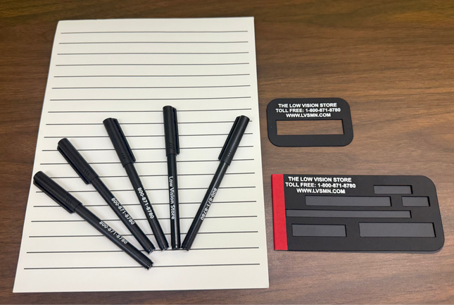 low vision writing aids kit with bold line paper, bold pens, signature guide and check writing guide on wooden desk