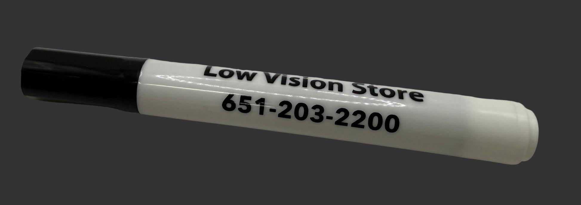 White marker with black cap on a white surface, displaying 'Low Vision Store' and phone number.