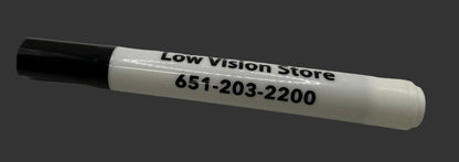 White marker with black cap on a white surface, displaying 'Low Vision Store' and phone number.