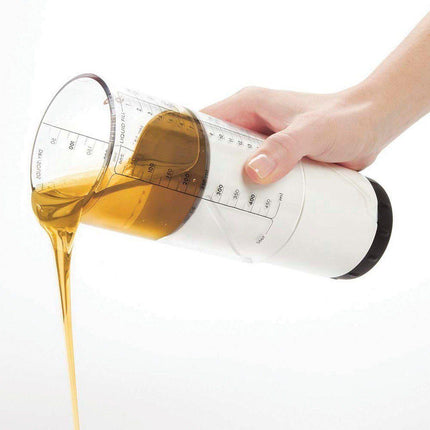 Hand pouring liquid from an adjustable measuring cup for low vision, showcasing ingredients being dispensed accurately.