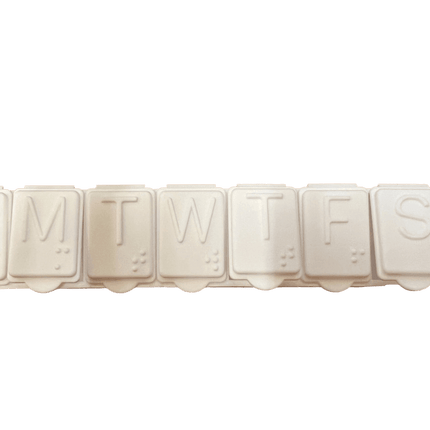 Brailled weekly pill organizer with compartments for each day of the week, featuring standard letters and Braille markings.