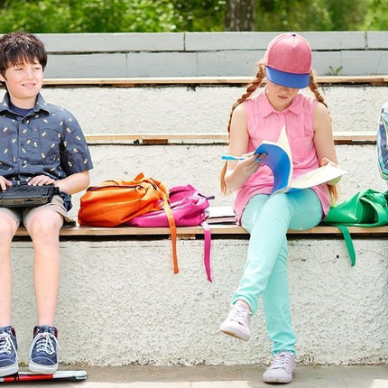 Children using a Braille notetaker with 32-cell display and studying outdoors.