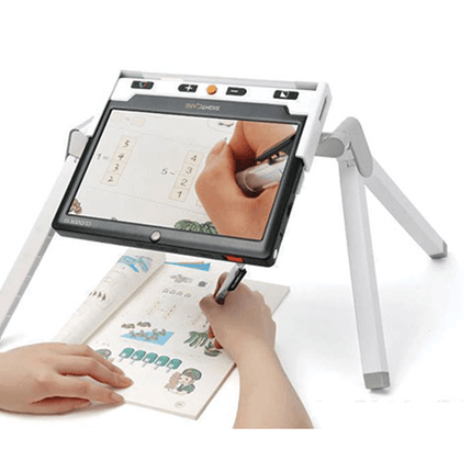 Clover 10 HD video magnifier with optional stand, showing a user writing on paper with the device.