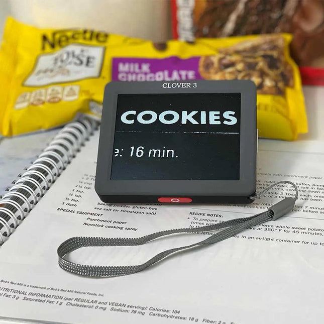 Clover 3 handheld video magnifier displaying text on a background of cookies and a notebook, portable video magnifier for easy reading.