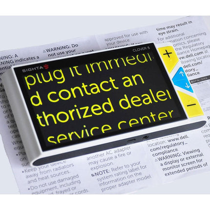Handheld video magnifier Clover 5 displaying instructions on a warning label with large text for visibility.