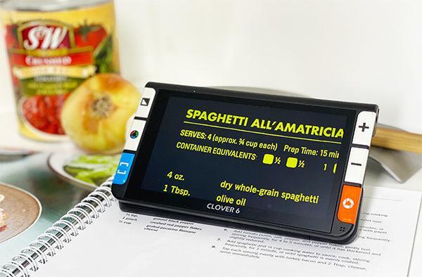 Clover 6 HD handheld video magnifier displaying a recipe for Spaghetti All'Amatriciana in bright text.