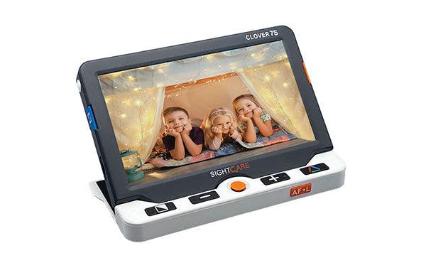 Clover 7 video magnifier displaying three children in a well-lit setting with festive lights in the background.