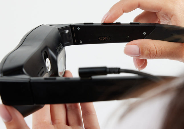 Close-up of eSight Go low-vision headset being held, showcasing its design and functionality for low vision assistance.