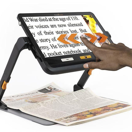 Portable video magnifier for low vision in use with a hand adjusting the display while reading a magazine.