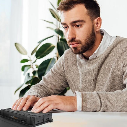 User interacting with Humanware Brailliant BI 20X braille display at a modern workspace.