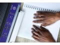 Hands using the Juliet 120 braille embosser with Tactile View software on blank paper.