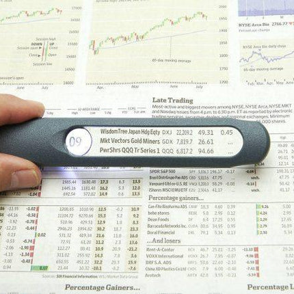 LED magnifier with spot lens illuminating stock market report for easy reading.