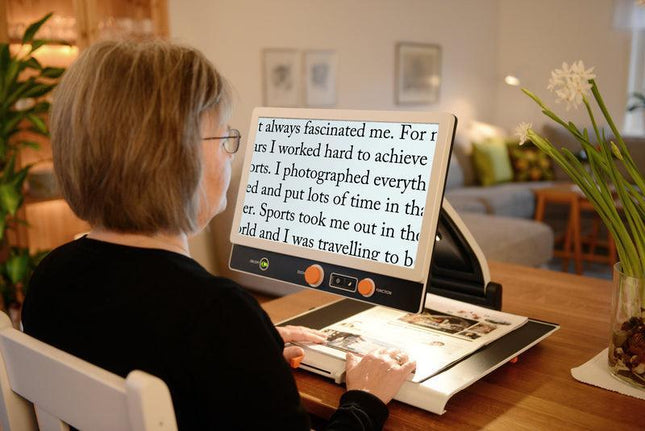 Person using Magni Link Zip Premium video magnifier to read text comfortably while seated at a desk.