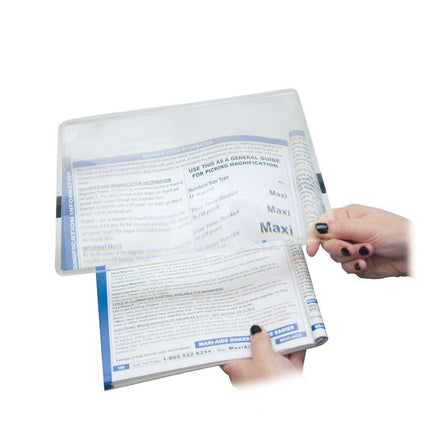User demonstrating 2x page magnifier over reading material for enhanced visibility and clarity.