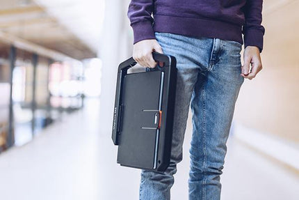 Person carrying a portable tablet solution for distance viewing in a modern hallway.