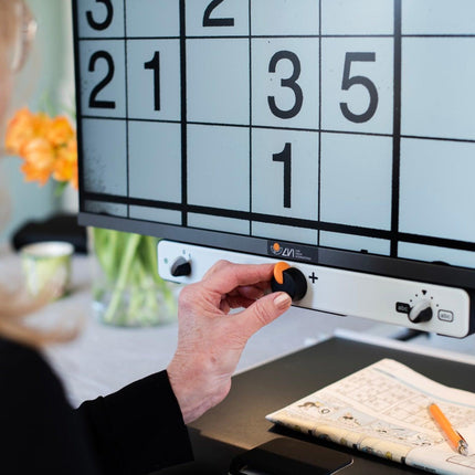 User adjusting settings on the MagniLink Vision HD 27" video magnifier for low vision.