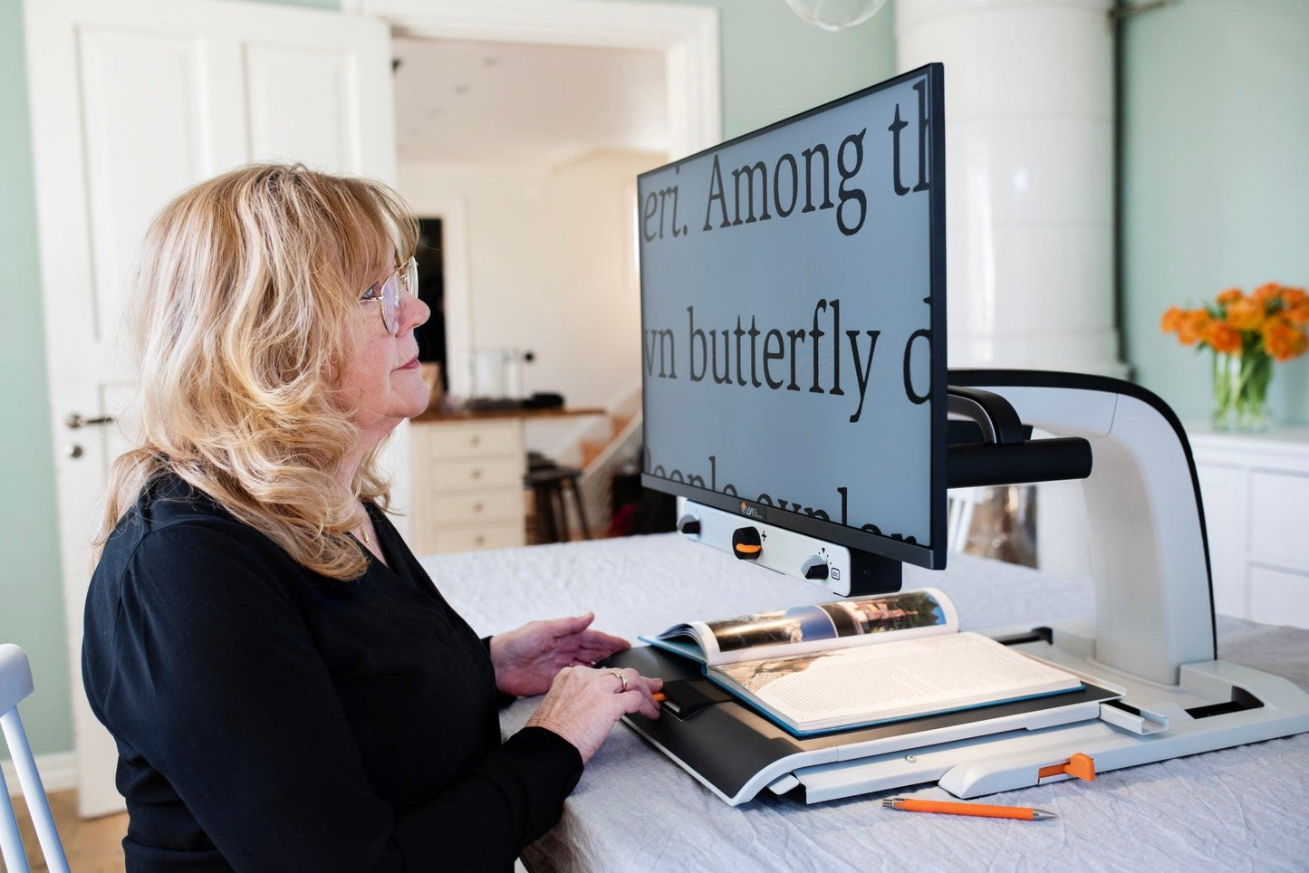 User operating an HD video magnifier for low vision to read a book with enlarged text.