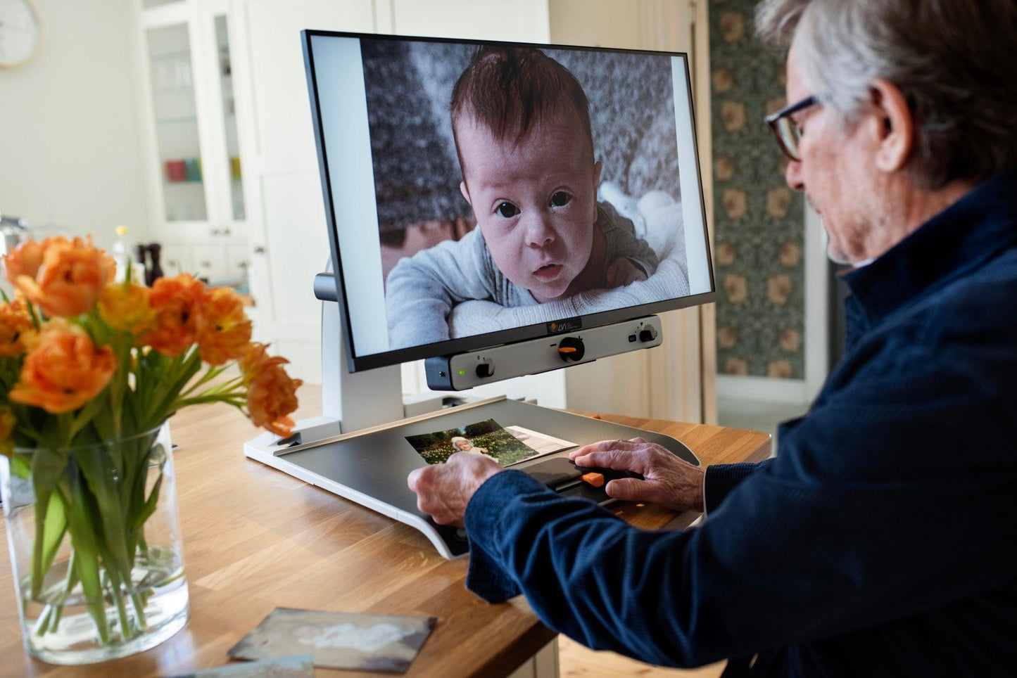 User operating the Magnilink Vision HD 27" video magnifier for low vision, viewing images clearly.