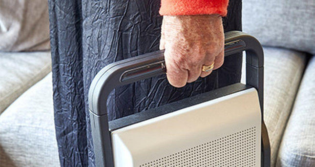 Hand holding the MagniLink Voice 2 text to speech device, showcasing its portability and compact design.