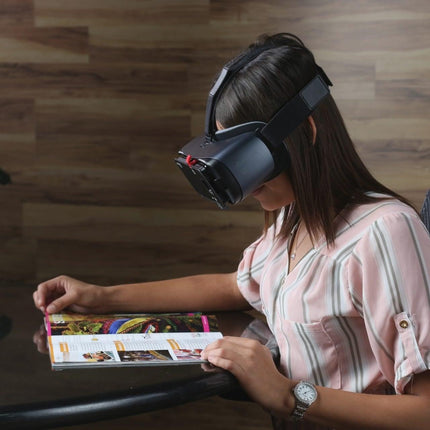Woman using the Patriot View Point hands-free magnification device to read a magazine.