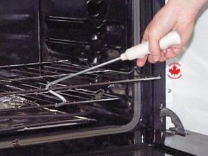 Person using a push pull stick for limited mobility to move an oven rack in a kitchen.