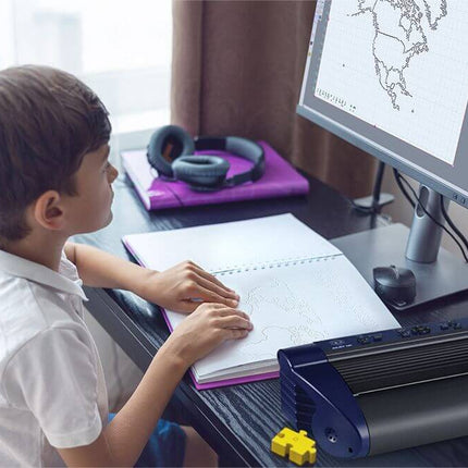 Child using the Romeo 60 braille embosser for tactile documents with computer and notepad at home.