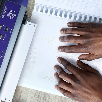 Hands using the Romeo 60 braille embosser for tactile documents, showcasing braille printing process on the page.