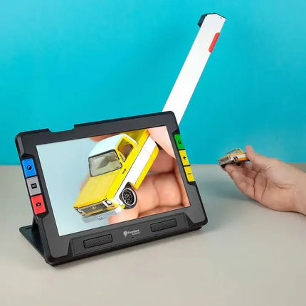 RUBY 10 portable video magnifier for low vision displaying a miniature yellow car and hand holding another toy car.