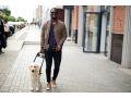 A person walking a dog on the street, showcasing a stylish outfit and enjoying a casual urban stroll.