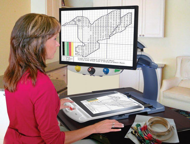 Woman using Topaz XL HD 24" Desktop Video Magnifier for easy viewing and crafting activities.