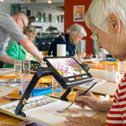 USED Explore 8 handheld electronic magnifier being used by a senior artist during a painting class.
