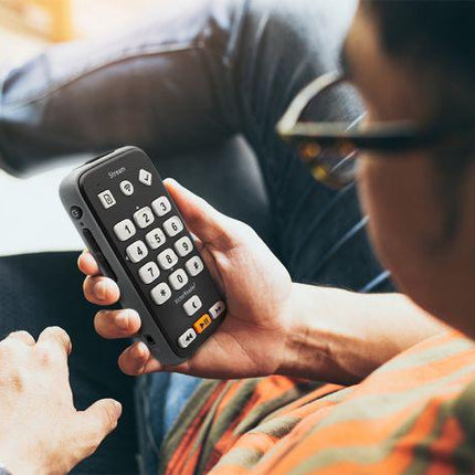 User holding the Victor Reader Stream 3, a handheld digital audio player for blind, featuring tactile buttons.